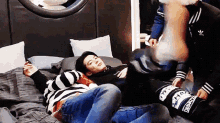 a group of young men are laying on a bed with one wearing a jacket that says adidas