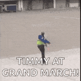 a man in a safety vest is standing on a runway holding a traffic cone and saying timmy at grand march .