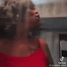 a woman in a red bra is making a funny face while standing in a kitchen .