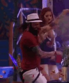 a man in a red shirt and white hat is dancing with a woman