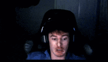 a man wearing headphones and a blue shirt is sitting in a chair