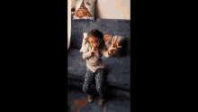 a little girl is sitting on a blue couch with a pillow that has the eiffel tower on it