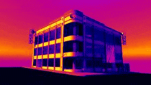 a thermal image of a building with a purple , orange and blue sky in the background .