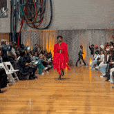 a man in a red dress is walking down a runway