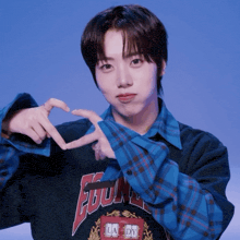 a young man wearing a shirt that says la dm makes a heart with his hands