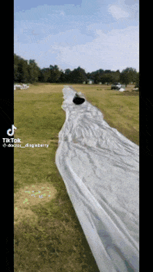 a person is walking down a long white sheet in a grassy field .