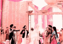 a group of people are dancing in a room with pink lights .