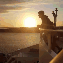 a man stands on a balcony looking at the sunset over the water