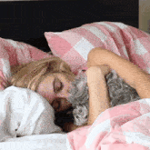 a woman is sleeping in bed with a dog