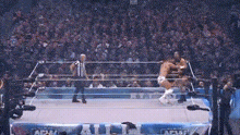 two wrestlers are fighting in a wrestling ring with a referee watching .