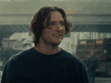 a man with long hair and a black shirt smiles