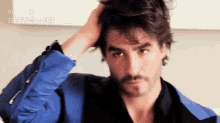 a man in a blue jacket is adjusting his hair with a reface app