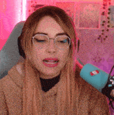 a woman wearing glasses and headphones stands in front of a blue microphone