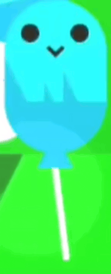 a blue balloon with a face on a stick is sitting on a green surface .