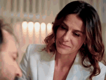 a woman in a white jacket looks at a man