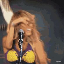 a woman singing into a microphone with a rbd.gif below her