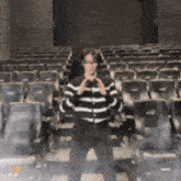 a man in a black and white striped sweater is standing in an auditorium