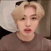 a young man with blonde hair and pink lips is wearing a purple shirt and sunglasses .