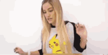 a woman wearing a pikachu t-shirt is standing in front of a white board .