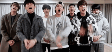 a group of young men are standing next to each other in a room and singing into microphones .