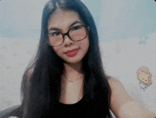 a woman wearing glasses and a necklace with the letter b on it