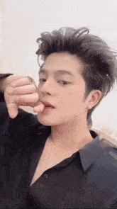 a young man wearing a black shirt and a ring on his finger is eating something .