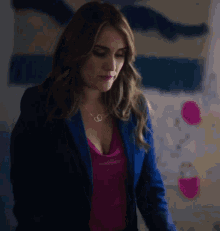 a woman is wearing a blue jacket and a pink shirt