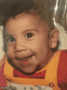 a baby is smiling and wearing a red and yellow outfit