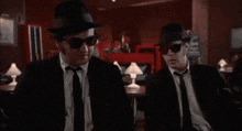 two men in suits and hats are standing next to each other with the words " we 're putting the band back together "