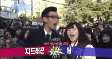a man and a woman are standing in front of a crowd with a sign that says ' top ' on it