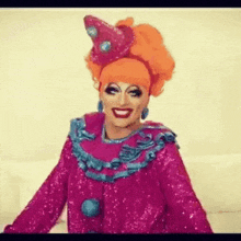 a drag queen is wearing a pink and blue clown costume .