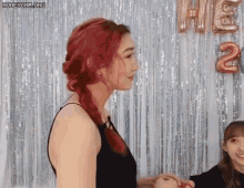 a woman with red hair is holding the hand of another woman .