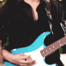a close up of a man playing a blue electric guitar .