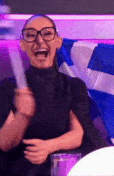 a woman wearing glasses is laughing and holding a piece of paper