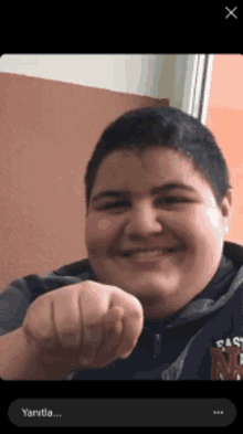 a boy with a hoodie that says california on it is smiling and pointing