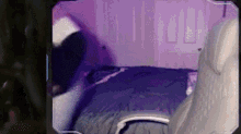 a person is sitting on a bed in a room with purple lights .