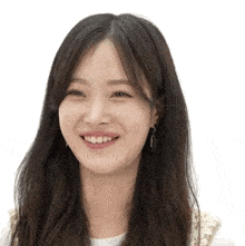 a woman with long black hair is smiling and wearing earrings