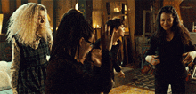 a group of women are standing in a room and one of them has dreadlocks on