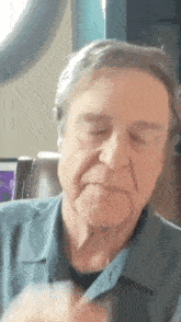 a man in a blue shirt is sitting in a chair with his eyes closed and his mouth open .