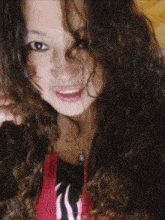 a girl with curly hair wearing a red jacket with a s on it