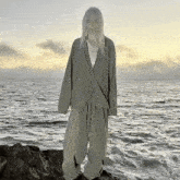 a woman with long blonde hair standing on a rock near the ocean