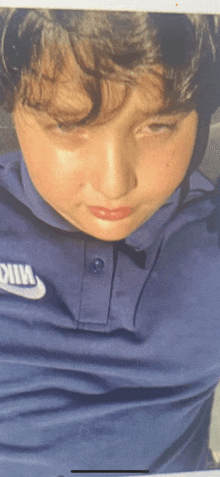a boy wearing a blue nike shirt is looking at the camera