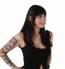 a woman with a lot of tattoos on her arms is wearing a black top .