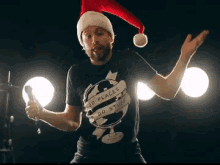 a man wearing a santa hat and a go places do stuff shirt is singing into a microphone