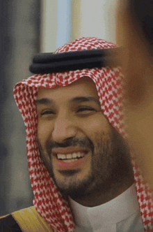 a man wearing a red and white checkered head scarf smiles for the camera