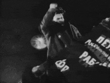 a black and white photo of a man holding a sign that says ' russian ' on it