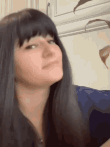a close up of a woman 's face with long black hair and bangs making a funny face .