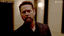 a man with a beard in a dark room with the word wildcards on the bottom