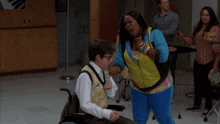 a man in a wheelchair is standing next to a woman in a yellow jacket