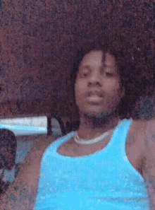 a man is wearing a blue tank top and a necklace